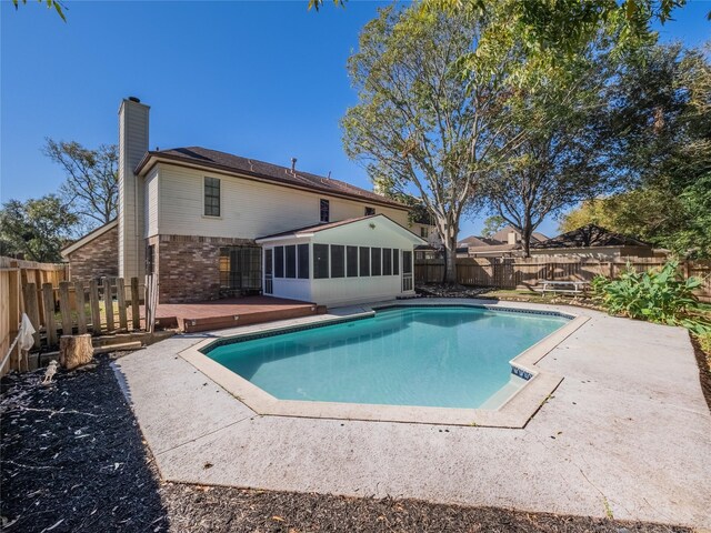 view of swimming pool with a sunroom and a wooden deck