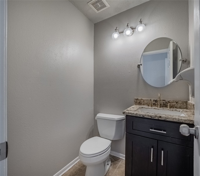 bathroom with toilet, vanity, and tile patterned floors