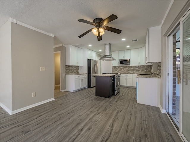 kitchen with stainless steel appliances, exhaust hood, white cabinetry, hardwood / wood-style flooring, and a kitchen island