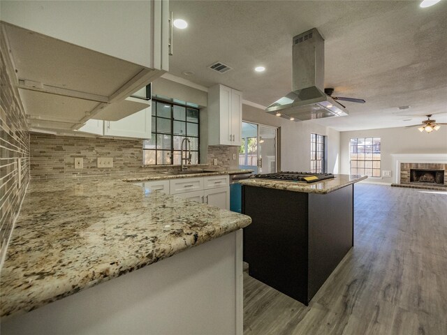 kitchen featuring wood-type flooring, a center island, island range hood, and white cabinetry