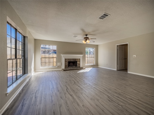 unfurnished living room with a fireplace, ceiling fan, hardwood / wood-style floors, and a textured ceiling