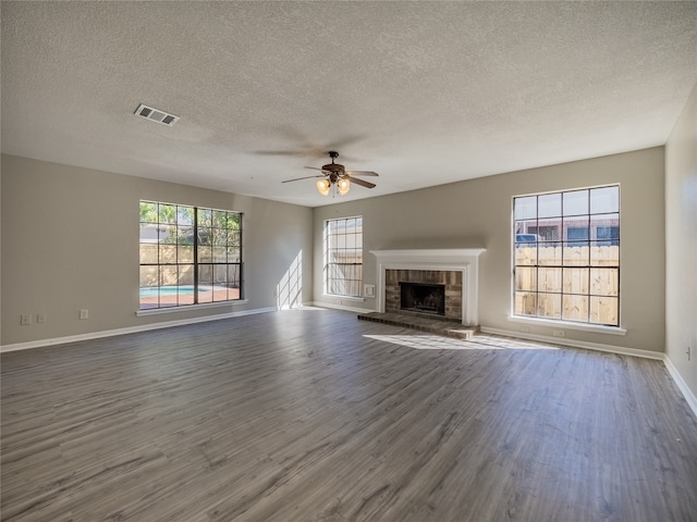 unfurnished living room featuring a fireplace, ceiling fan, dark hardwood / wood-style flooring, and a textured ceiling