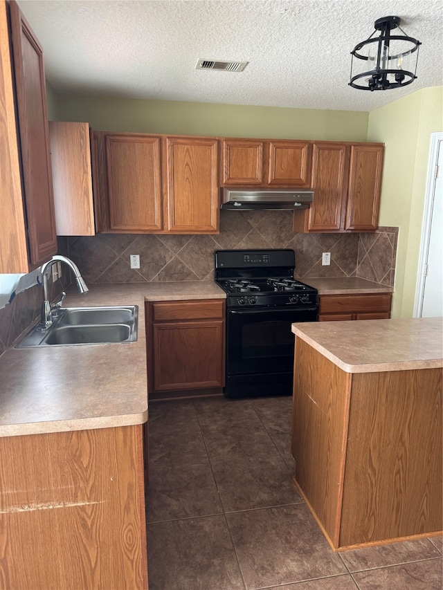 kitchen featuring tasteful backsplash, black range with gas stovetop, a textured ceiling, sink, and an inviting chandelier