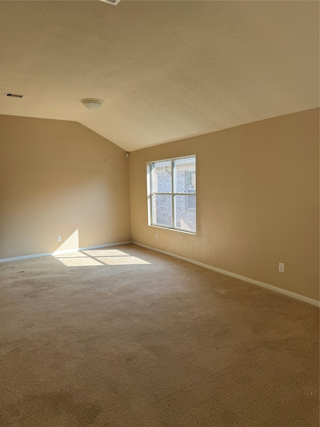 spare room featuring carpet, a textured ceiling, and lofted ceiling