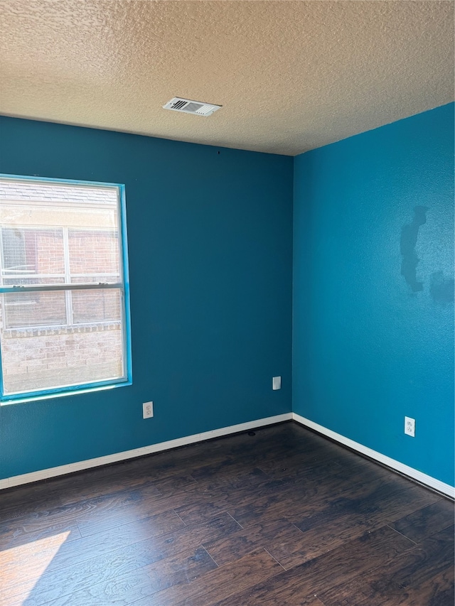 empty room featuring a textured ceiling and dark wood-type flooring