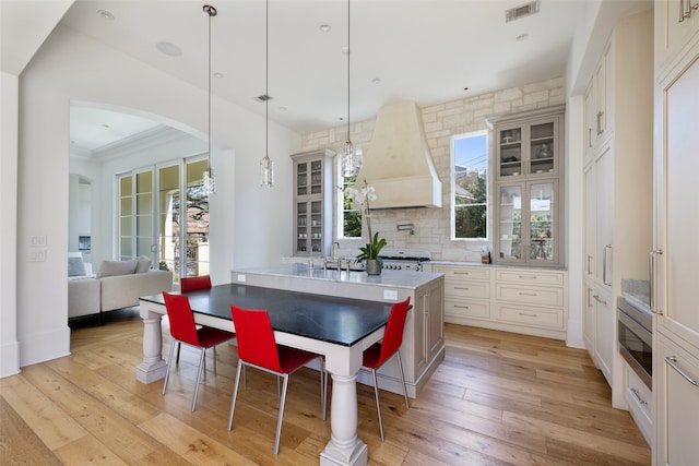 kitchen featuring pendant lighting, custom exhaust hood, light wood-type flooring, and a wealth of natural light