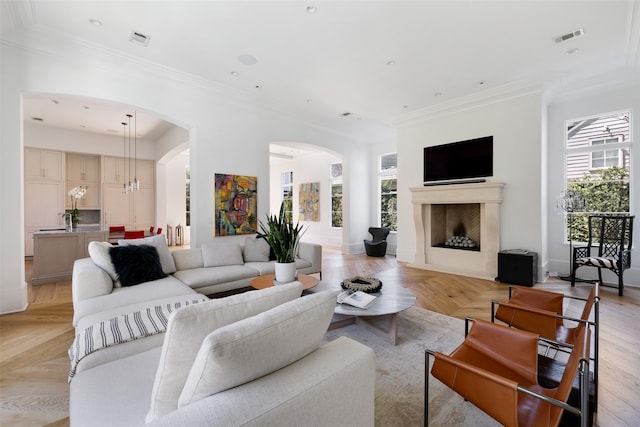 living room featuring a notable chandelier, crown molding, and a wealth of natural light