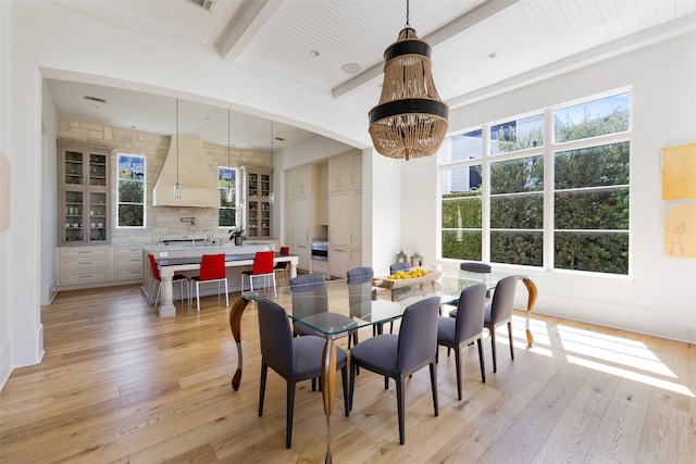 dining space featuring beam ceiling, wooden ceiling, a healthy amount of sunlight, and light wood-type flooring