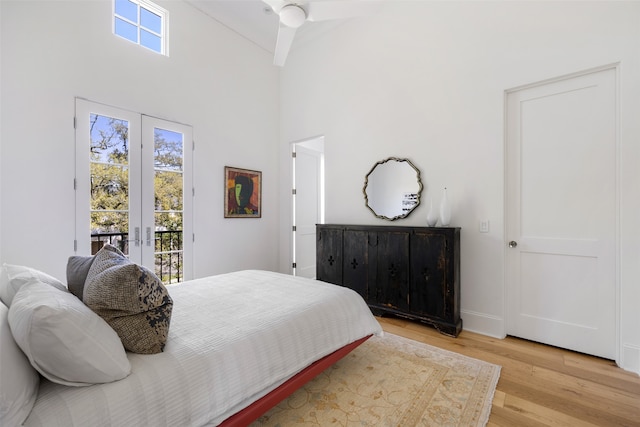 bedroom featuring ceiling fan, light hardwood / wood-style flooring, high vaulted ceiling, and multiple windows