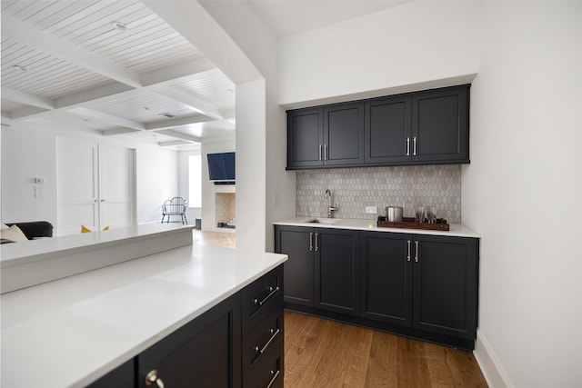 kitchen featuring tasteful backsplash, sink, wood-type flooring, and beam ceiling