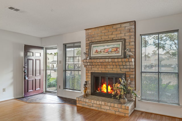 living room featuring a fireplace, wood-type flooring, and a textured ceiling