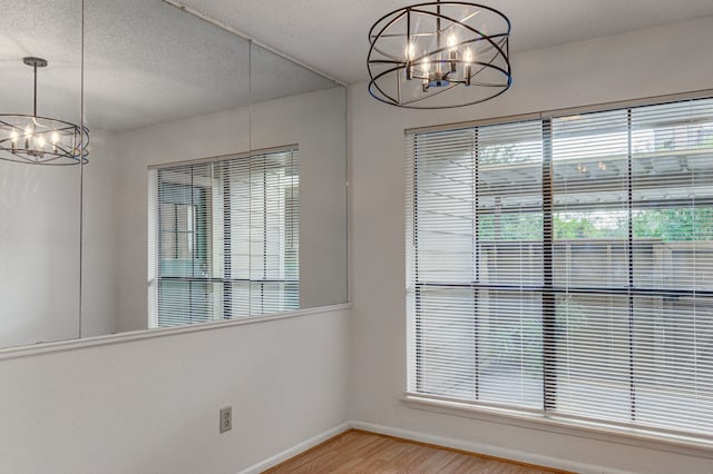 unfurnished dining area featuring a chandelier and wood-type flooring