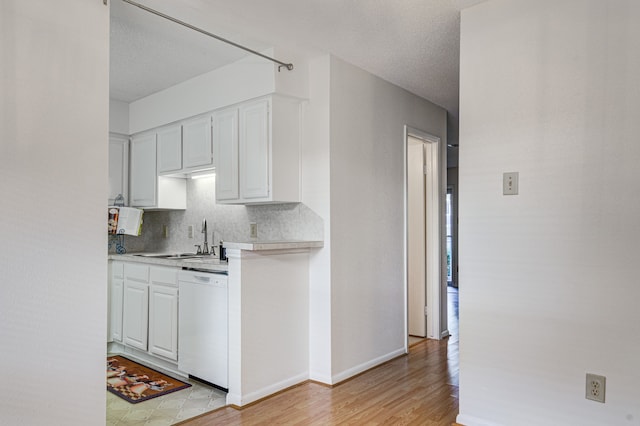 kitchen featuring sink, light hardwood / wood-style flooring, backsplash, white dishwasher, and white cabinets