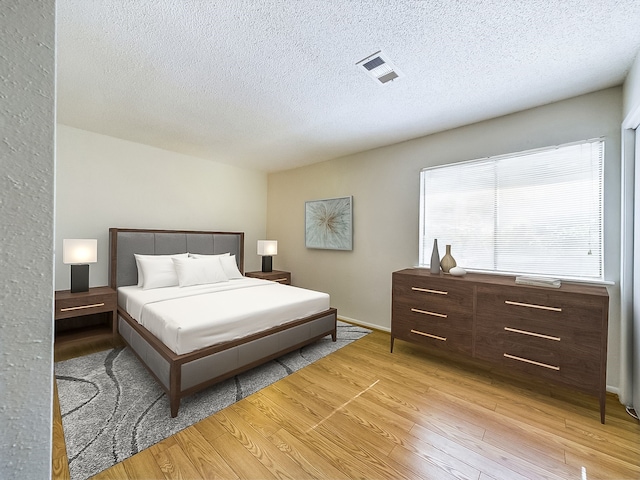 bedroom with a textured ceiling and light wood-type flooring