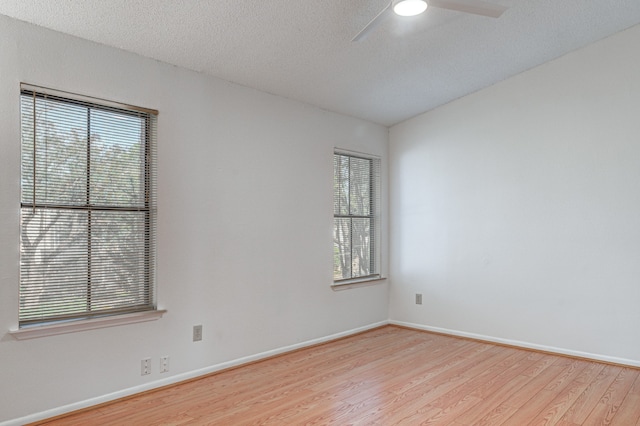 spare room featuring ceiling fan, plenty of natural light, a textured ceiling, and light wood-type flooring