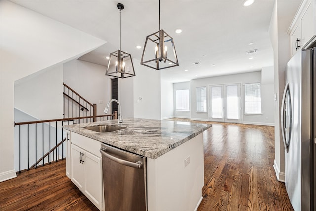 kitchen with white cabinets, appliances with stainless steel finishes, a center island with sink, and sink