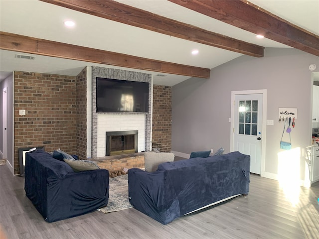 living room featuring hardwood / wood-style floors, lofted ceiling with beams, and a brick fireplace