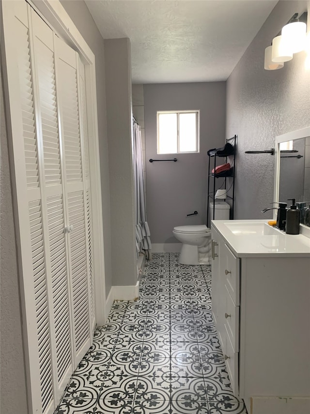 bathroom featuring tile patterned flooring, vanity, toilet, and walk in shower