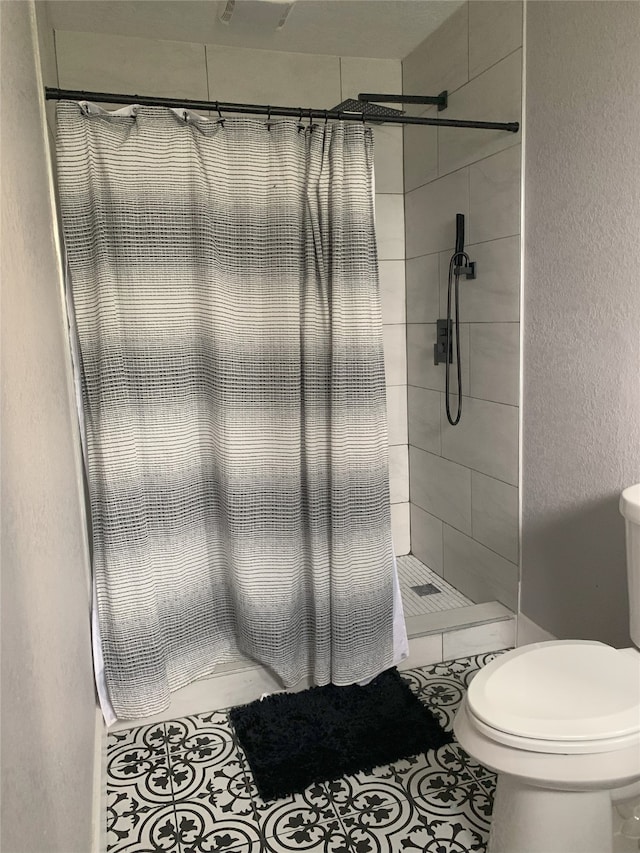 bathroom with tile patterned floors, toilet, and walk in shower