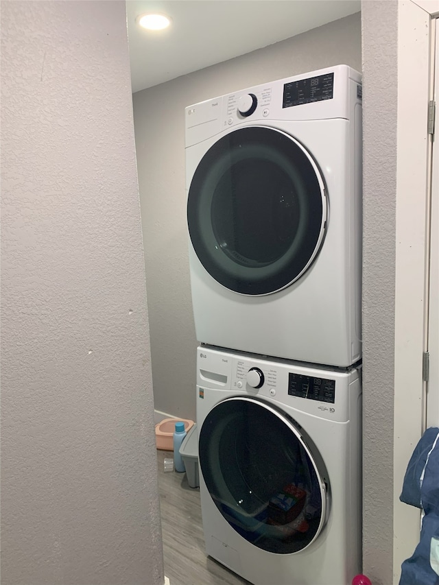 laundry room featuring light wood-type flooring and stacked washing maching and dryer