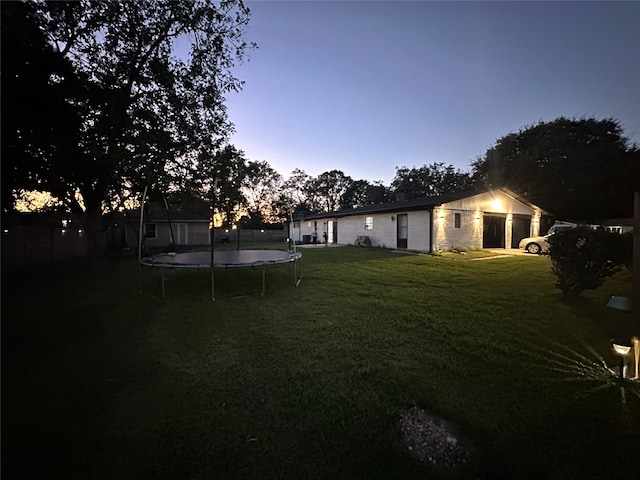 yard at dusk featuring a trampoline