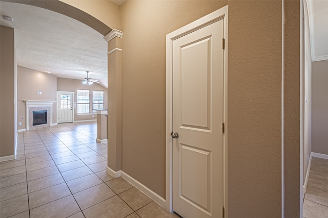 hall with vaulted ceiling, ornate columns, light tile patterned floors, and a textured ceiling