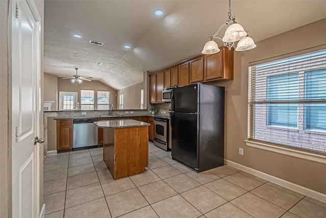 kitchen with a center island, kitchen peninsula, lofted ceiling, ceiling fan with notable chandelier, and appliances with stainless steel finishes