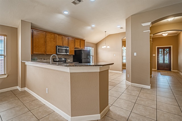 kitchen featuring kitchen peninsula, decorative backsplash, stainless steel appliances, vaulted ceiling, and pendant lighting