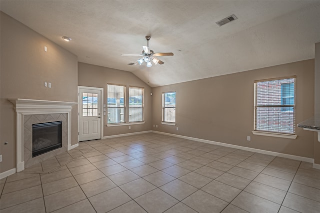 unfurnished living room featuring a fireplace, lofted ceiling, a healthy amount of sunlight, and light tile patterned flooring