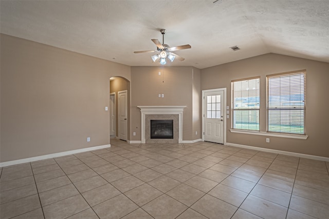 unfurnished living room featuring a textured ceiling, vaulted ceiling, ceiling fan, light tile patterned floors, and a tiled fireplace