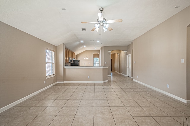 kitchen with kitchen peninsula, black fridge, vaulted ceiling, ceiling fan, and light tile patterned flooring