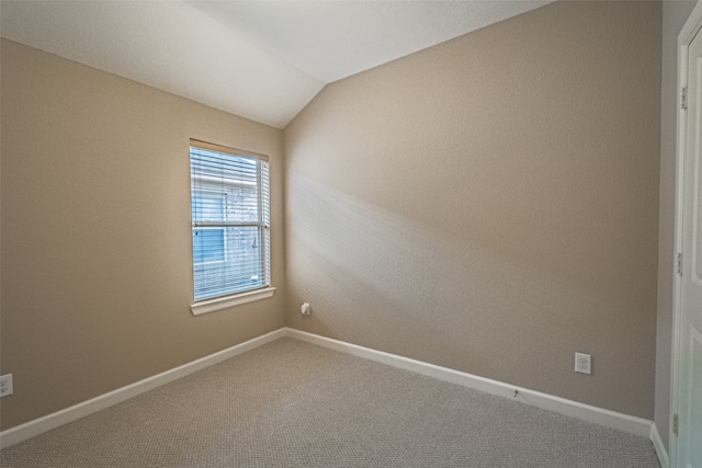 carpeted empty room featuring lofted ceiling