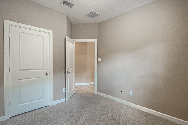 unfurnished bedroom with light colored carpet and a textured ceiling