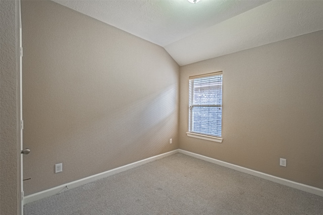 carpeted empty room featuring lofted ceiling