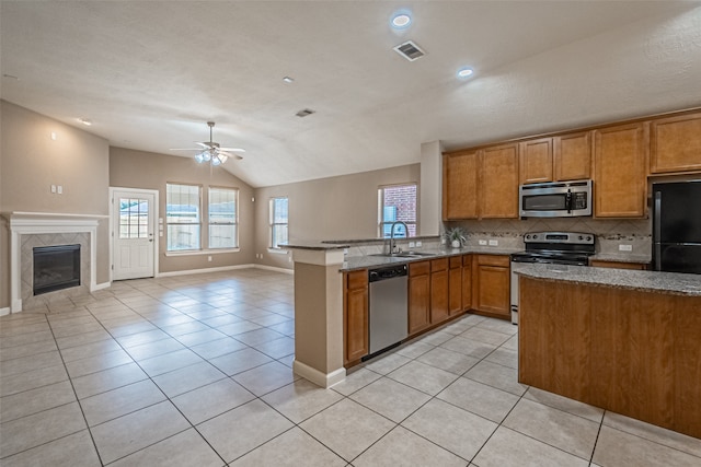 kitchen featuring kitchen peninsula, appliances with stainless steel finishes, vaulted ceiling, ceiling fan, and light tile patterned floors