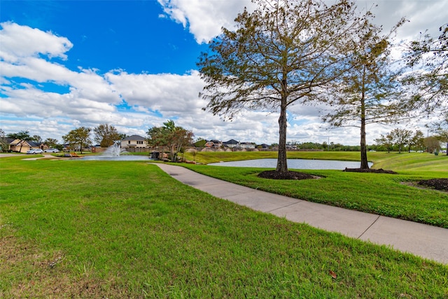 view of home's community with a water view and a lawn