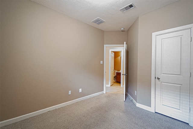 unfurnished bedroom with a textured ceiling and light colored carpet