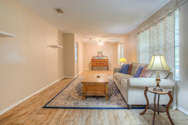 living area with a ceiling fan, visible vents, baseboards, and wood finished floors