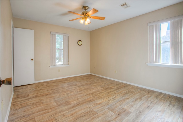 empty room with a wealth of natural light, light hardwood / wood-style flooring, and ceiling fan