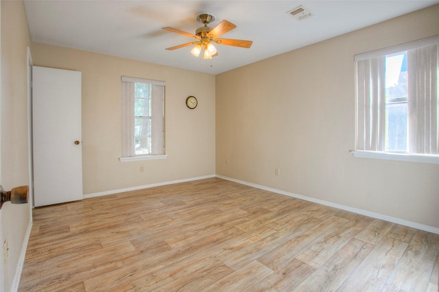 empty room with baseboards, a ceiling fan, visible vents, and light wood-style floors