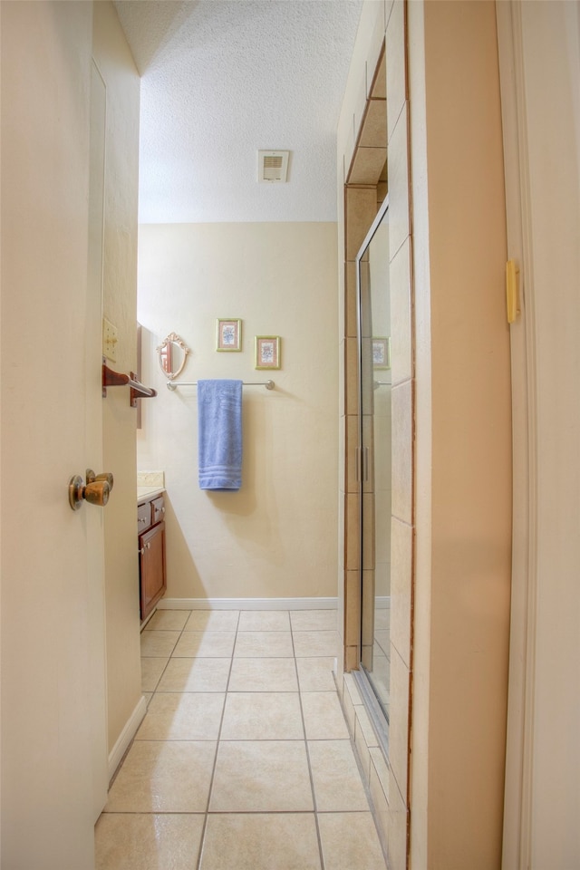 bathroom featuring tile patterned floors, a textured ceiling, vanity, and an enclosed shower