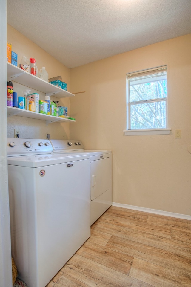 clothes washing area with light hardwood / wood-style flooring, washer and dryer, and a textured ceiling