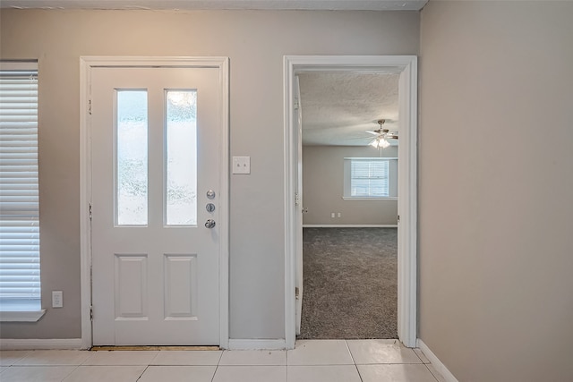 entrance foyer featuring ceiling fan, light tile patterned floors, and a textured ceiling