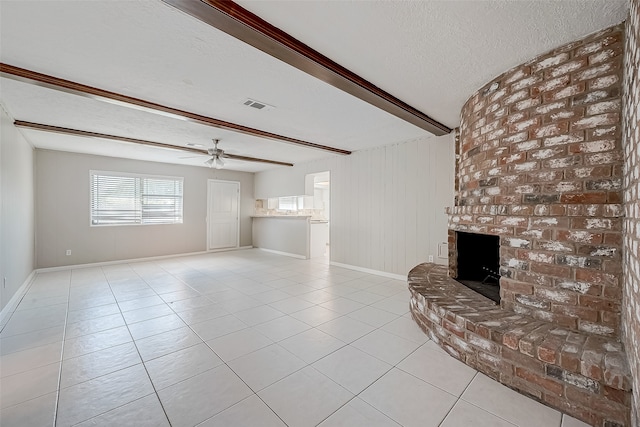 unfurnished living room with a fireplace, beam ceiling, light tile patterned floors, and a textured ceiling