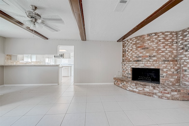 unfurnished living room featuring beamed ceiling, light tile patterned floors, a textured ceiling, and a fireplace