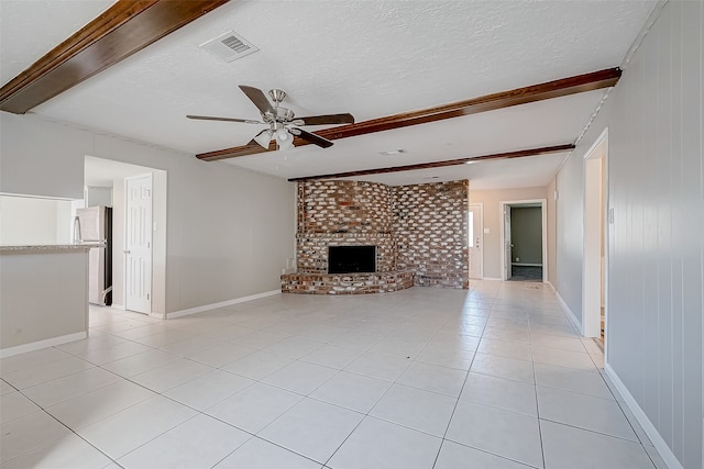 unfurnished living room with ceiling fan, light tile patterned floors, a textured ceiling, a fireplace, and beam ceiling