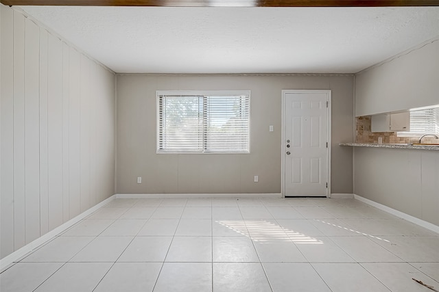 empty room featuring wooden walls, light tile patterned floors, and a wealth of natural light