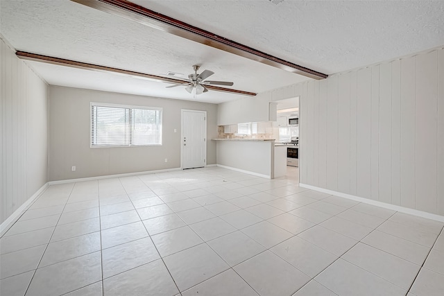 unfurnished living room with beamed ceiling, ceiling fan, light tile patterned floors, and a textured ceiling