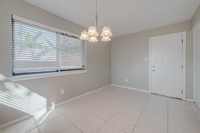 tiled spare room featuring a notable chandelier