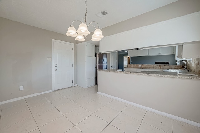 kitchen featuring sink, stainless steel fridge, pendant lighting, a chandelier, and light tile patterned floors